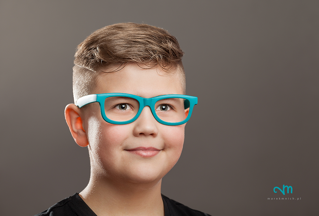 Teenager boy with eyeglasses on grey background